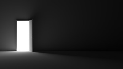 Grayscale shot of an open door letting light into a dark room